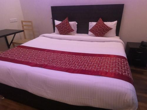 a large bed with red and white sheets and pillows at Venster Residency in Chennai