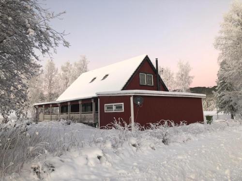 a red barn with snow on top of it at Villa Stolle in Hammarstrand