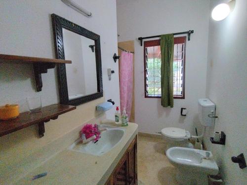 a bathroom with a sink and a toilet and a mirror at Villa 36 Karibuni in Malindi