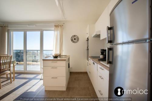 a kitchen with a stainless steel refrigerator and a window at Apartment with swimming pool and garage in a standing residence in Nice