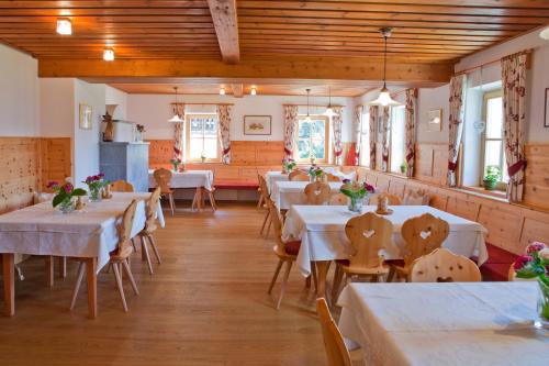 a dining room with white tables and wooden ceilings at Lienharterhof in Monguelfo
