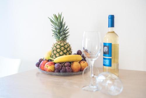 a bowl of fruit with a bottle of wine and a glass at Le Palme in Malia