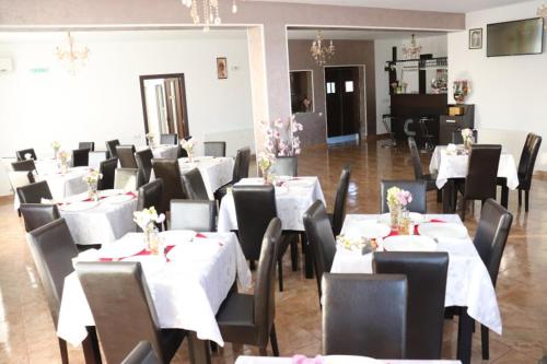 Pensiunea Crin-Tania في Mioveni: غرفة طعام مع طاولات بيضاء وكراسي سوداء