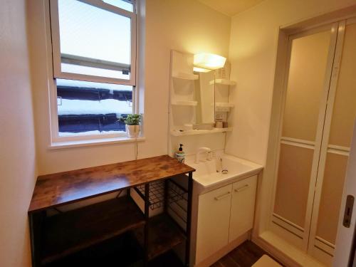 a bathroom with a sink and a window at Opopo home 堺町店 in Otaru