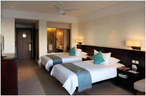 a hotel room with two beds and a television at Howard Johnson Resort Sanya Bay in Sanya