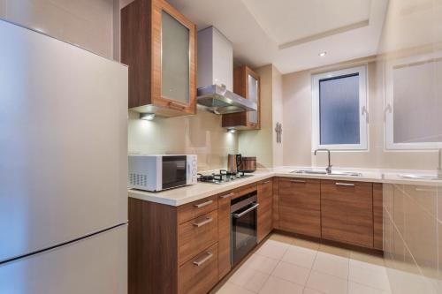 a kitchen with wooden cabinets and a white refrigerator at Sanya Yikehai View Apartments in Sanya