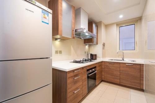a kitchen with a white refrigerator and wooden cabinets at Sanya Yikehai View Apartments in Sanya