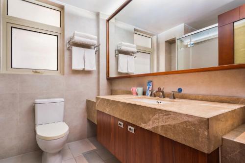 a bathroom with a sink and a toilet and a mirror at Sanya Yikehai View Apartments in Sanya