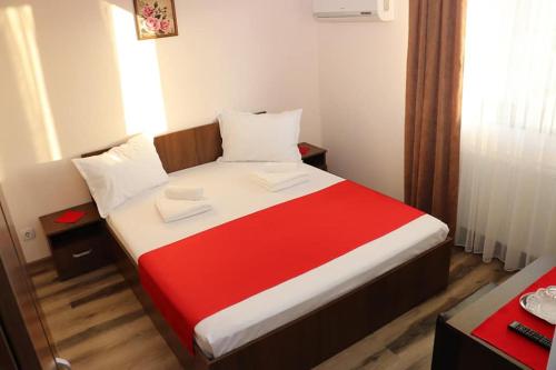 um quarto com uma cama com um cobertor vermelho e branco em Pensiunea Crin-Tania em Mioveni