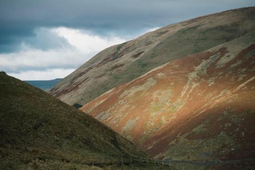 a brown hill with green grass on the side of it at Westmorland Hotel Tebay in Tebay