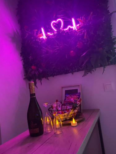 L’appart[é] BLACK superbe appartement pop ! في بيزنسون: زجاجة من النبيذ موضوعة على طاولة مع ضوء وردي
