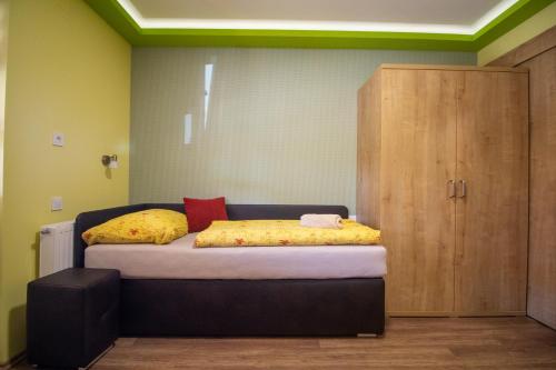 a bedroom with a bed with yellow sheets and a cabinet at Radics Panzió Étterem és Pihenő Központ in Letenye