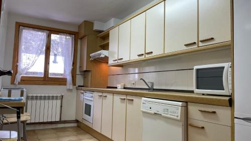 une cuisine avec des armoires blanches et un micro-ondes dans l'établissement Apartamento turístico Nievesol 24 - Benasque, à Benasque