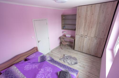 a bedroom with a purple bed and a cat laying on the floor at Mici Luxury Apartments in Ledine