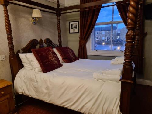 a bedroom with a four poster bed with a window at Old Hall Hotel Hope in Hope
