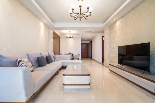 a living room with a white couch and a tv at Sanya Yikehai View Apartments in Sanya