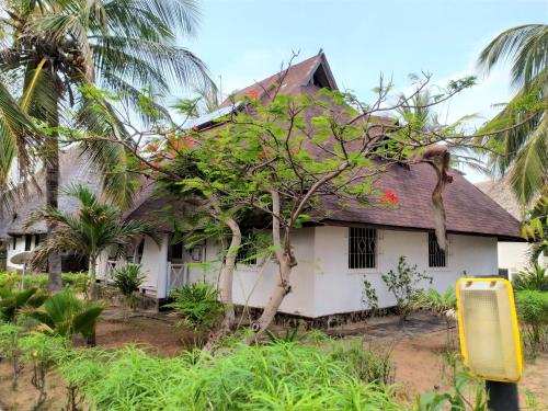 a white house with a tree in front of it at Mambrui Villa 34, Villa 36 in Malindi