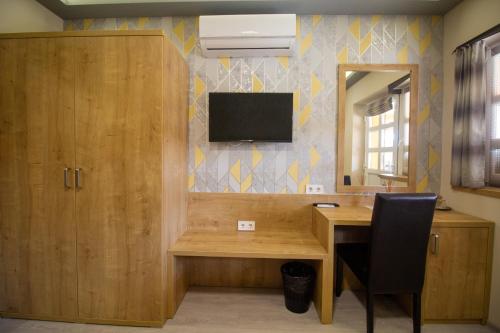 a room with a desk and a television on a wall at Radics Panzió Étterem és Pihenő Központ in Letenye