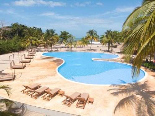 a swimming pool with chaise lounges and beach chairs at Tay Beach Hotel Tayrona in Buritaca