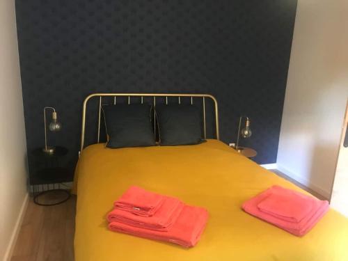 南特的住宿－La Janvraie，一张黄色的床,上面有两条粉红色的毛巾