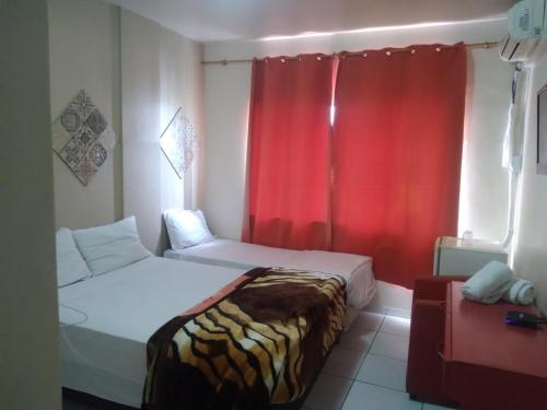a bedroom with two beds and a red curtain at Fronteira Hotel in Santana do Livramento