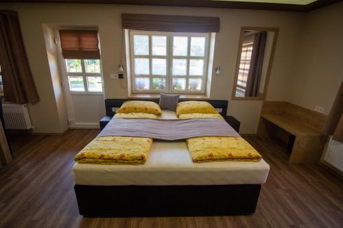 a bedroom with a large bed and two windows at Radics Panzió Étterem és Pihenő Központ in Letenye