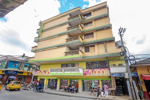 シンセレホにあるHotel Merylandの街の通りに立つ背の高い黄色い建物と人々