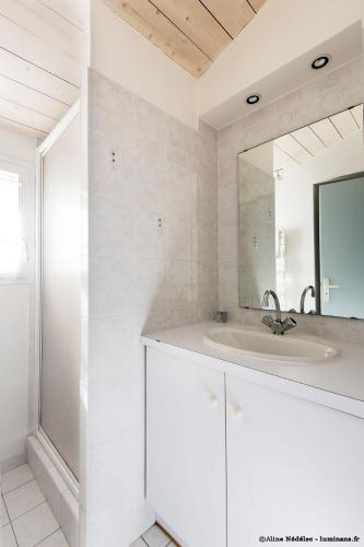 une salle de bain blanche avec un lavabo et un miroir dans l'établissement Maison Aumière, à La Flotte