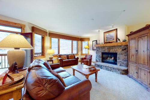 a living room with a leather couch and a fireplace at Antlers in Steamboat Springs