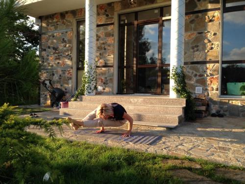 a person doing a yoga pose in front of a house at Zapovedni Rai in Primorsko