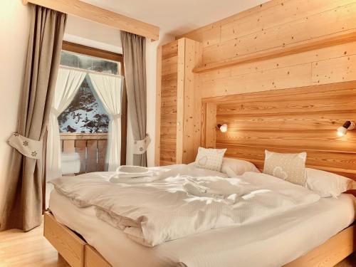 a large white bed in a room with a window at Eurochalet in Campitello di Fassa