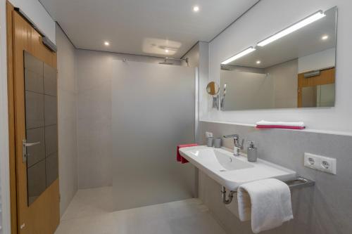 a white bathroom with a sink and a mirror at Ferienwohnungen Alpentraum - Hirschsprung in Bolsterlang