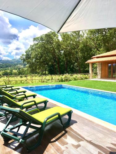 a pool with lounge chairs and an umbrella at Casa de Pelicas - Celorico de Basto in Celorico de Basto