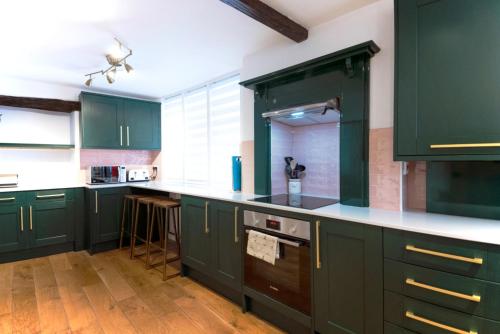 a kitchen with green cabinets and white counter tops at Host & Stay - Iris Cottage in Pickering