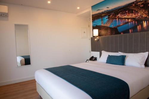 a bedroom with a bed with a painting on the wall at Hotel Porto Interface Trindade By Kavia in Porto