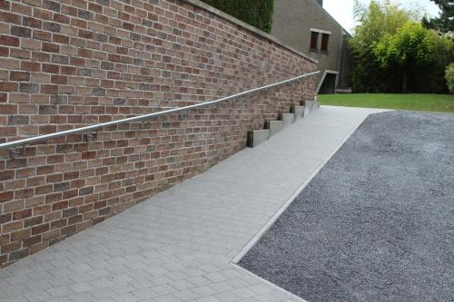 a brick building with a sidewalk next to a brick wall at Éco Gîtes Aubelrando & villa-bocage in Aubel