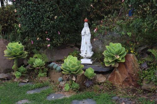 a statue of a woman in a garden with plants at Chalet en la montaña in Cogua