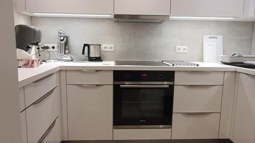 a kitchen with white cabinets and a black oven at Apartment und Ferienwohnung, Wohnen auf Zeit, Kurring 8, Bad Rodach in Bad Rodach