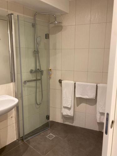 a bathroom with a shower and a sink with towels at Hotel Porto Interface Trindade By Kavia in Porto