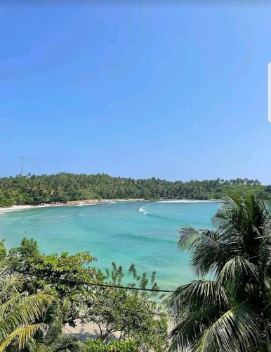 a view of a beach with palm trees and the ocean at Waves Hiri Sea View in Hiriketiya