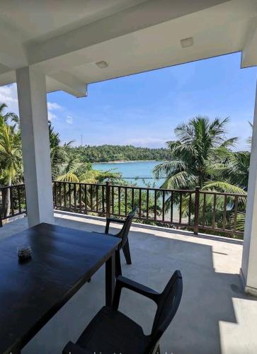 a porch with a table and chairs and a view of the ocean at Waves Hiri Sea View in Hiriketiya