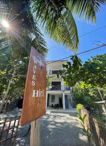 a sign in front of a building with a palm tree at Waves Hiri Sea View in Hiriketiya