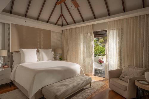 a bedroom with a large white bed and a couch at Four Seasons Resort Mauritius at Anahita in Beau Champ