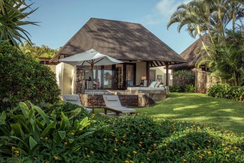 a house with chairs and an umbrella on a yard at Four Seasons Resort Mauritius at Anahita in Beau Champ
