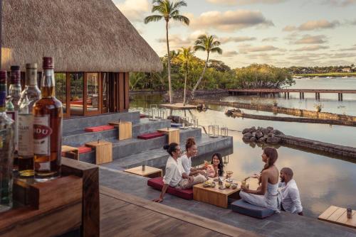 um grupo de pessoas sentadas em torno de uma mesa em frente a uma piscina em Four Seasons Resort Mauritius at Anahita em Beau Champ