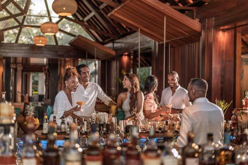 a group of people standing around a bar with drinks at Four Seasons Resort Mauritius at Anahita in Beau Champ