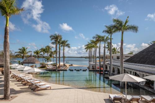 a resort with a pool and palm trees and chairs at Four Seasons Resort Mauritius at Anahita in Beau Champ