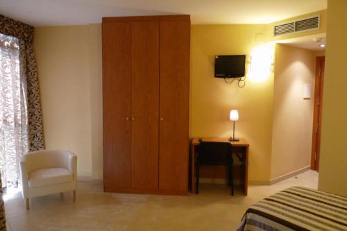 a bedroom with a cabinet and a chair and a desk at Hotel Avenida El Morell in El Morell