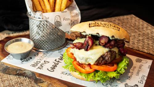 a hamburger with bacon and tomatoes on a table with fries at ibis Barranquilla in Barranquilla
