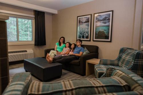 a family sitting on a couch in a living room at Mountaineer Lodge in Lake Louise